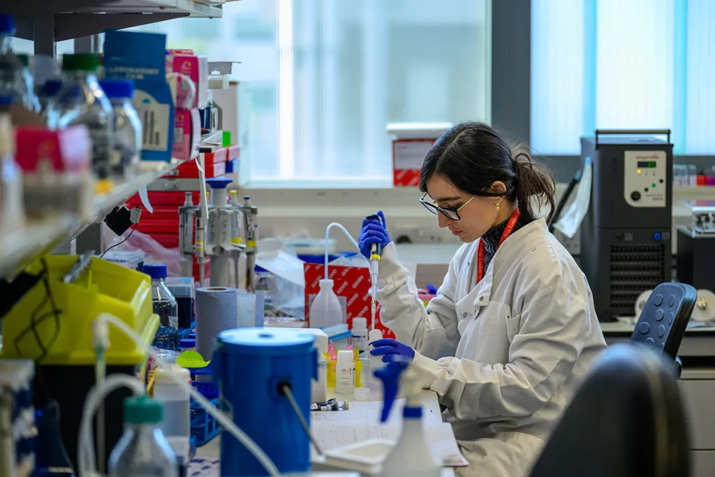 Scientist in lab coat working at lab bench.
