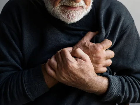 Man holding hand against chest.